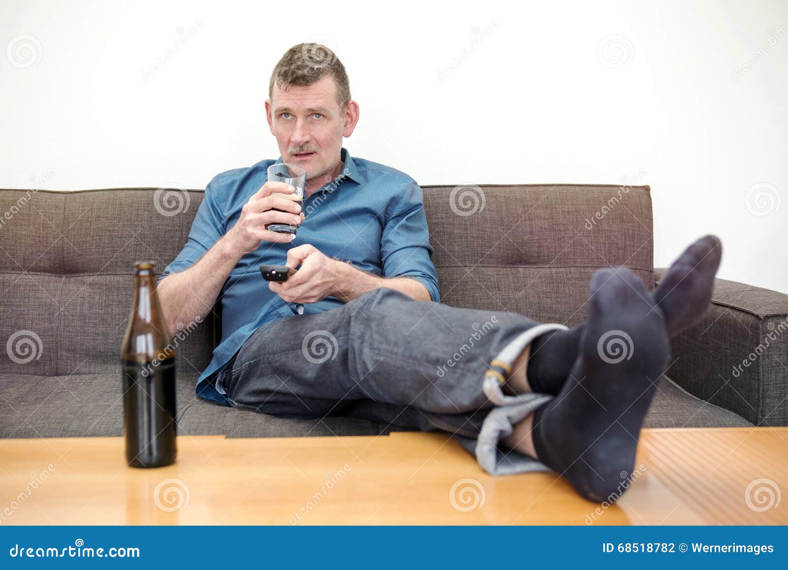 man-sitting-couch-watching-tv-drinking-beer-68518782.jpg